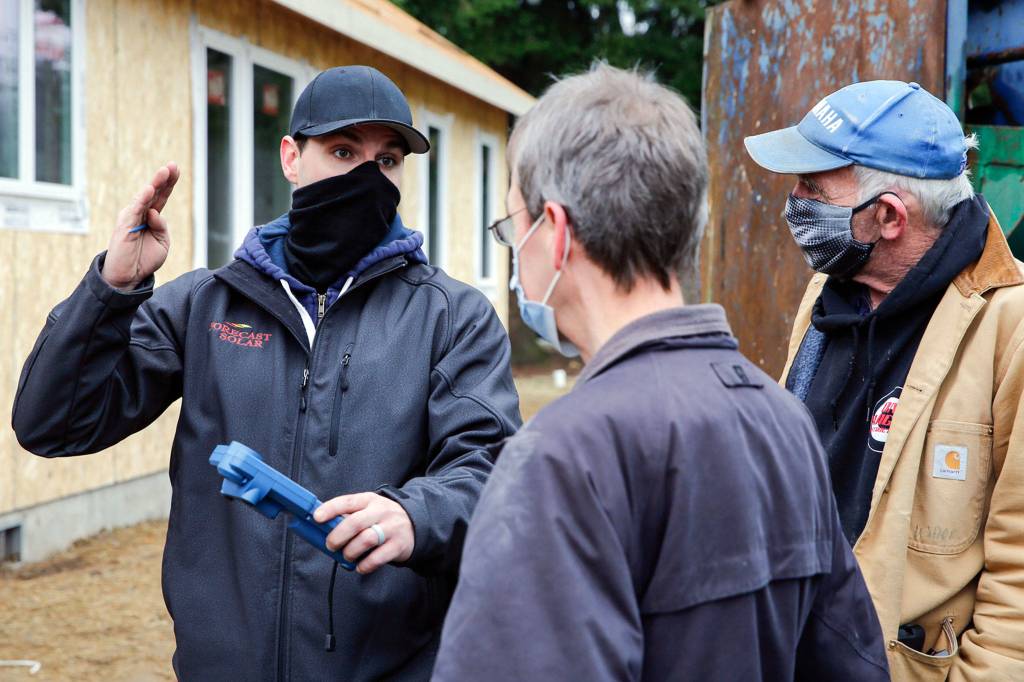 Morgan Zehrung (left), owner of Forecast Solar, talks with homeowner Brian Aikins and builder Jeff Harrell in Everett. (Kevin Clark / The Herald)