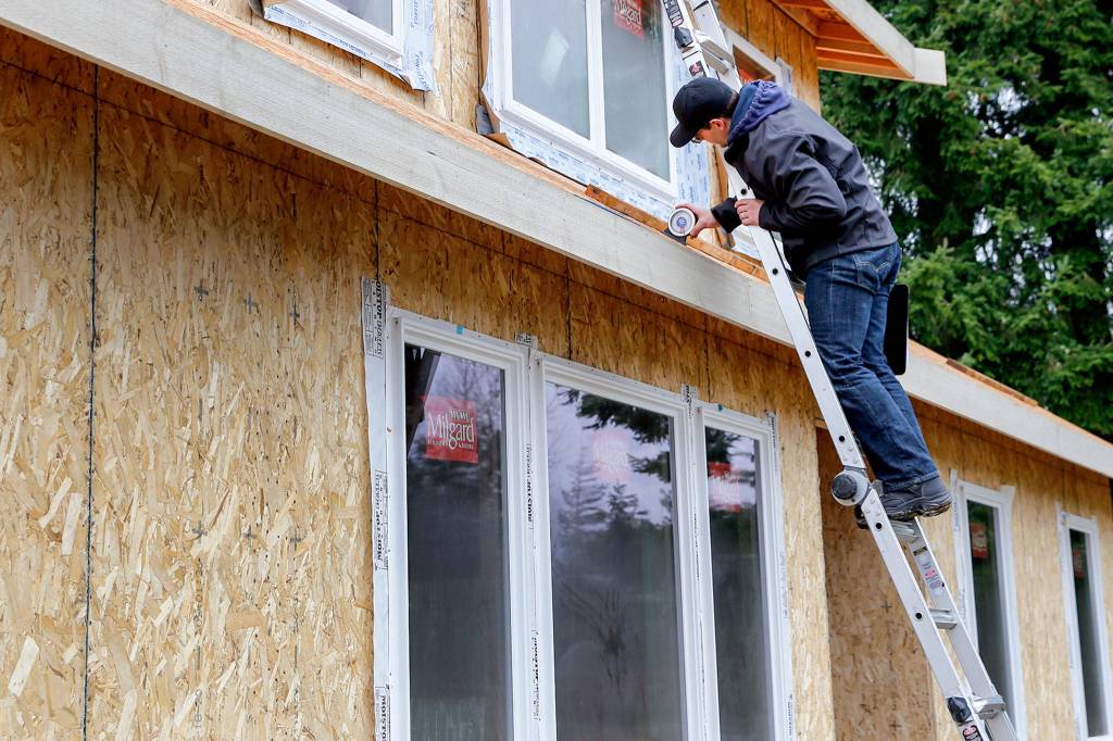 Morgan Zehrung, owner of Forecast Solar, takes measurements for solar panels on a home in Everett. (Kevin Clark / The Herald)