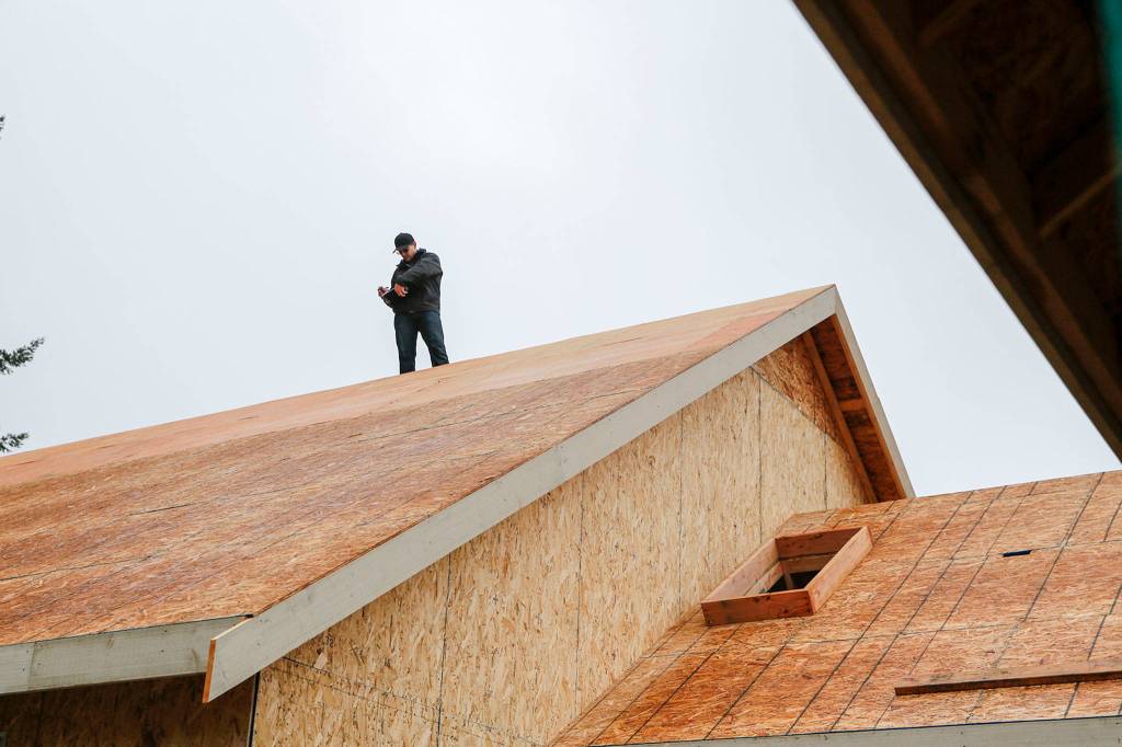 Morgan Zehrung, owner of Forecast Solar, takes measurements for solar panels on a home in Everett. (Kevin Clark / The Herald)
