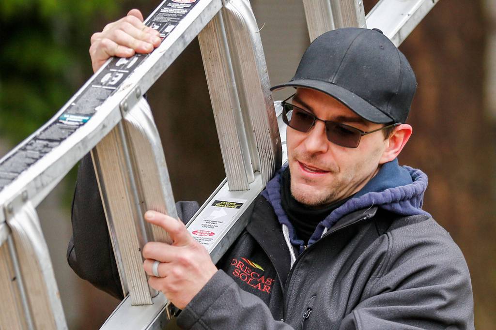 Morgan Zehrung, owner of Forecast Solar, at work at the home of Brian Aikins in Everett. (Kevin Clark / The Herald)