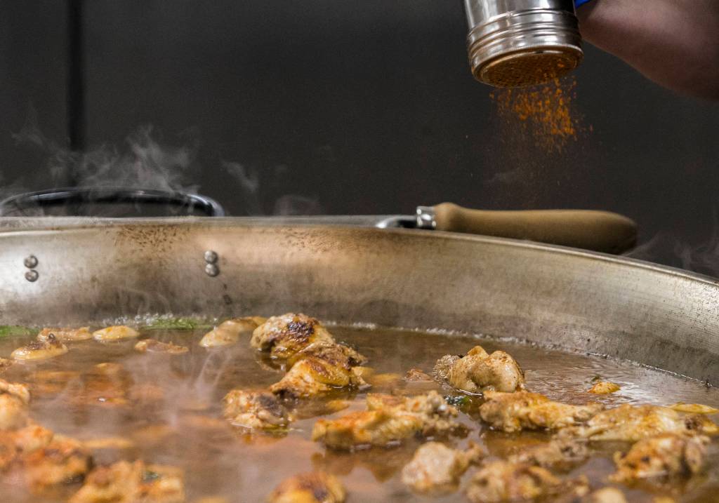 Paprika is added to a Paella Valenciana, which is based on the original paella recipe found in an 18th-century manuscript. (Olivia Vanni / The Herald)