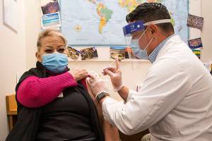 Alicia Ramos gets her first shot of the Modern COVID-19 vaccine from Pharmacy Director Jeremy Thompson at QFC on Thursday, Feb. 4, 2021 in Edmonds, Washington.  (Andy Bronson / The Herald)