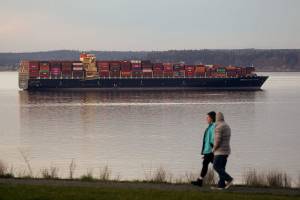 A couple walks around Harborview Park as the  Seaspan Brilliance, a 1,105-foot cargo ship, moors near the Port of Everett on Wednesday, Feb. 3, 2021 in Everett, Washington.  The ship is moored until it can offload its cargo in Vancouver, B.C. (Andy Bronson / The Herald)