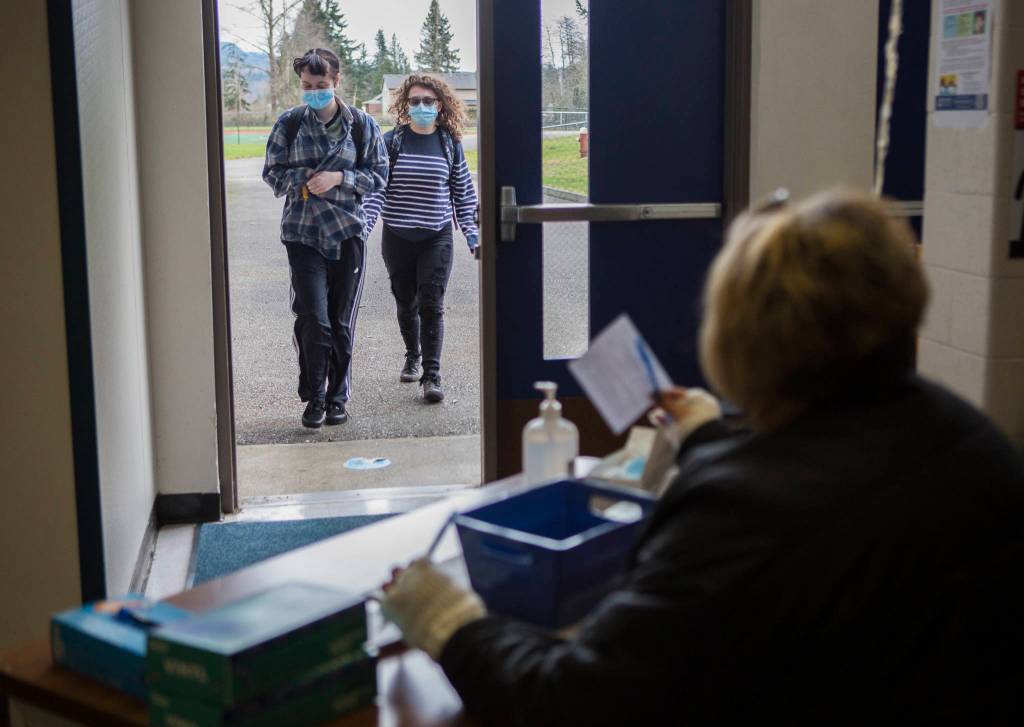 Students approach a checkpoint where they must fill out a wellness survey before having their temperatures checked at Sultan High School. (Olivia Vanni / The Herald)