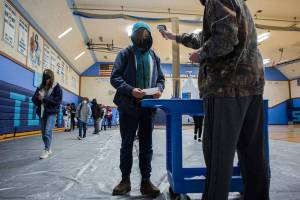 Sultan High School students line up, social distanced at one of the three temperature and wellness check station set up in the gym before entering the school for classes on Thursday, Feb. 11, 2021 in Sultan, Wa. (Olivia Vanni / The Herald)