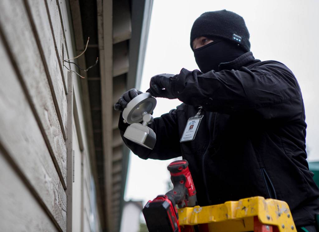 Aaron Perkins works on outdoor light fixtures at Tomorrows Hope Child Development Center in Everett. (Olivia Vanni / The Herald)