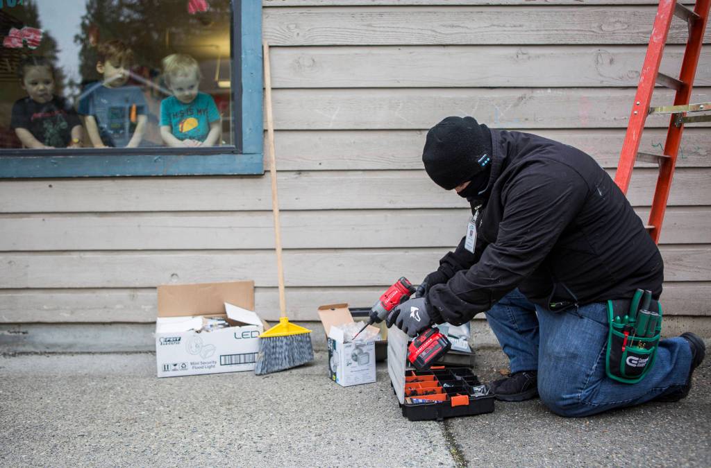 Children watch from a window as Aaron Perkins looks for screws in his toolbox. (Olivia Vanni / The Herald)