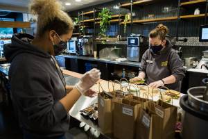 Shianne Shelton, left, and Jennifer Smith, right, prep sandwich lunches to be delivered to the volunteers the the Arlington Airport COVID-19 vaccination site on Friday, Feb. 12, 2021 in Everett, Wa. (Olivia Vanni / The Herald)