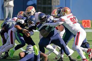 Seattle Seahawks quarterback Russell Wilson, left, is tackled as offensive guard Damien Lewis, right, blocks San Francisco 49ers defensive end Arik Armstead (91) during the first half of an NFL football game, Sunday, Nov. 1, 2020, in Seattle. (AP Photo/Elaine Thompson)