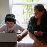 Alma López watches her son Eric Blanquet do school work Friday afternoon in Lake Stevens. (Kevin Clark / The Herald)