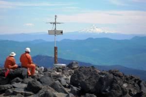 Karl Hagel and Pat McChesney, field engineers with the Pacific Northwest Seismic Network team at the University of Washington, install earthquake monitoring equipment on the slopes of Mount St. Helens, with Mount Hood in the distance. (Marc Biundo / University of Washington)
