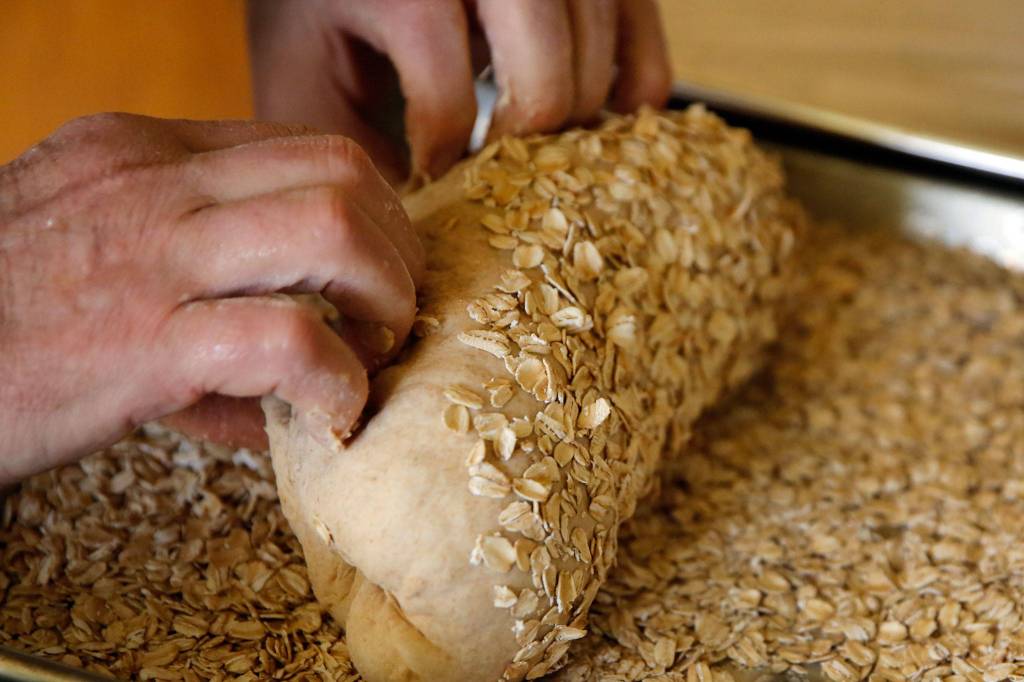 Gerry Betz rolls bread in oats Saturday morning at his home in Everett. (Kevin Clark / The Herald)