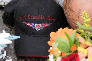 Rain drops gather on a ball cap with the name of the crab fishing boat Scandies Rose, a 130-foot crab fishing boat from Dutch Harbor, Alaska, that sank on New Year's Eve, as the hat rests near some flowers and a fishing float at the Seattle Fishermen's Memorial, Thursday, Jan. 2, 2020, in Seattle. (AP Photo/Ted S. Warren)
