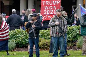 FILE - In this Jan. 6, 2021, file photo at the Capitol in Olympia, Wash., two men stand armed with guns in front of the Governor's Mansion during a protest supporting President Donald Trump and against the counting of electoral votes in Washington, DC, affirming President-elect Joe Biden's victory. The open carry of guns and other weapons would be banned on the Capitol campus and at or near any permitted public demonstration across Washington under a measure being considered by Washington lawmakers. (AP Photo/Ted S. Warren, File)