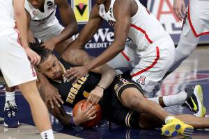 Arizona guard Bennedict Mathurin (0), left, and center Christian Koloko (35) smother Washington forward Nate Roberts (1) as they fight for a loose ball goes to the ground in the second half of an NCAA college basketball game Saturday, Feb. 27, 2021, in Tucson, Ariz. (Kelly Presnell/Arizona Daily Star via AP)