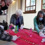 Julie Davis (left), Candice Jarrett (center) and Christine Edwards clean crystals for the reclaimed era chandelier Friday afternoon at the Carnegie Library in Snohomish. (Kevin Clark / The Herald)