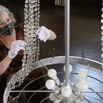 Renee Deierling attaches crystals to the reclaimed era chandelier Friday afternoon at the Carnegie Library in Snohomish. (Kevin Clark / The Herald)