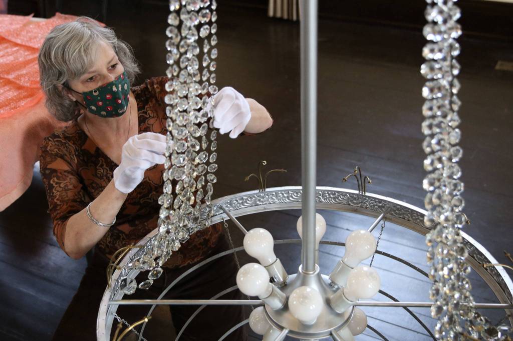Renee Deierling attaches crystals to the reclaimed era chandelier Friday afternoon at the Carnegie Library in Snohomish. (Kevin Clark / The Herald)