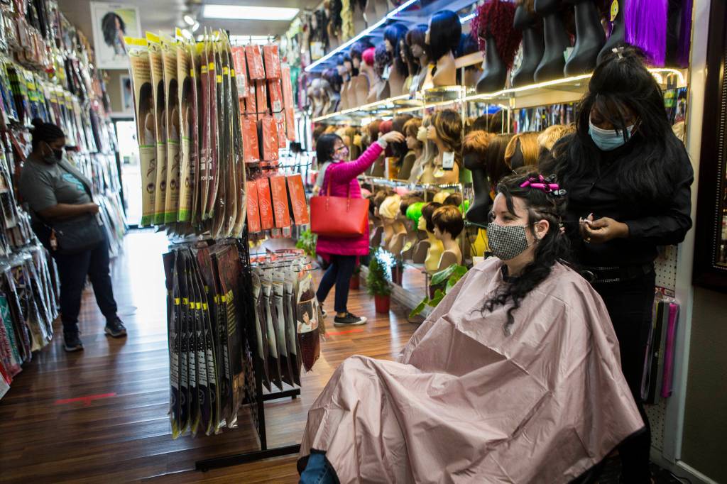 People browse wig and extension options while Decarla Stinn braids Hope Hottemdorfs hair. (Olivia Vanni / The Herald)