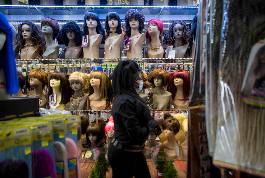 Decarla Stinn walks past rows of wigs on display in her store. (Olivia Vanni / The Herald)