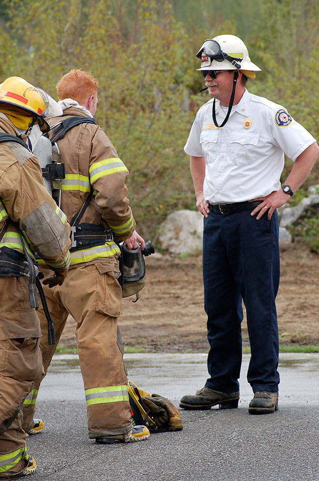 Isaac Howard (right) smiles during a training session with new recruits. Howard spent time as a training chief with Snohomish County Fire District 26 in Gold Bar. (Bobbie Lange)