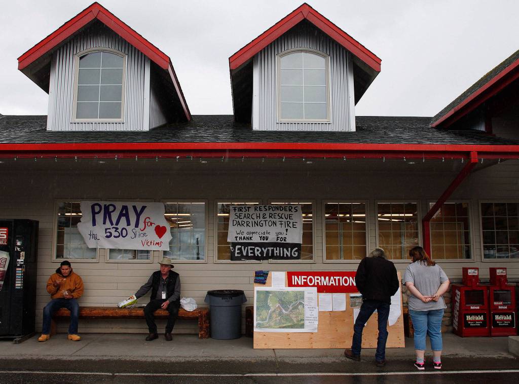 People gather outside the IGA grocery store to read the latest information on the Oso mudslide on Tuesday, March 25, 2014 in Darrington, Wash. (Genna Martin/The Herald)