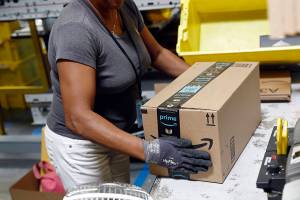 FILE - In this Aug. 3, 2017, file photo, an Amazon employee applies tape to a package before shipment at an Amazon fulfillment center in Baltimore. The online shopping giant, which already works with BP and Shell, has been trying to woo more oil and gas companies to use its technology to help them find drillable oil faster, angering workers who have been pushing Amazon to do more to combat climate change. (AP Photo/Patrick Semansky, File)