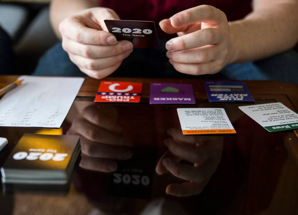 Jonathan Noble pulls a card from the deck as he demonstrates how to play through 2020: The Game. (Olivia Vanni / The Herald)