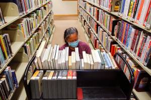 Darlene Tanis sorts through book titles Thursday morning at the Everett Library on March 4, 2021. (Kevin Clark / The Herald)