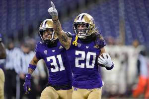 FILE - Washington's Asa Turner (20) celebrates with Kamren Fabiculanan (31) after Turner intercepted a pass in the final minute of an NCAA college football game against Oregon State in Seattle, in this Saturday, Nov. 14, 2020, file photo. Washington won 27-21. Washington has pulled out of the Pac-12 football championship game due to COVID-19 issues in the Huskies program, and Oregon will now play No. 13 USC for the conference title on Friday instead.  Washington (3-1) announced Monday, Dec. 14, 2020, it is withdrawing from the championship game after determining the Huskies did not have at least 53 scholarship players available and did not meet the minimum number of scholarship athletes at specific positions.(AP Photo/Ted S. Warren, File)