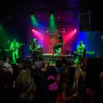 Michael Henrichsen, center, leaps across the stage as people dance during Nite Wave's show at Tony V's Garage on Saturday, June 8, 2019 in Everett, Wash. (Olivia Vanni / The Herald)