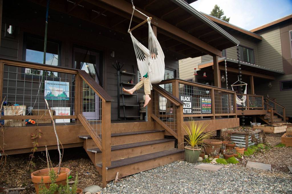Giacomo Brothers swings in a chair on the family porch at Clearwater Commons, a sustainable subdivision in Bothell. (Andy Bronson / The Herald)
