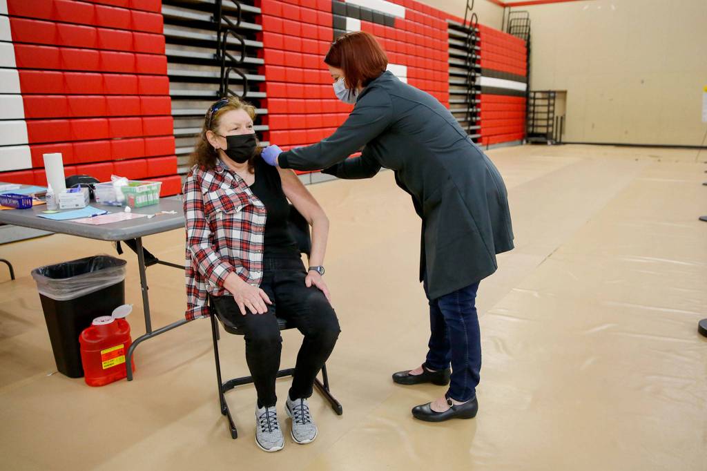 Eve Rutherford (right) administers Berinda Wolitarskys second vaccine shot Saturday morning at Snohomish High School. After becoming ill with COVID-19 last year, Wolitarsky nearly lost her battle to live. (Kevin Clark / The Herald)