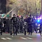 Tacoma Police and other law enforcement officials stand in a line as protesters approach in the street in front of the City-County Building during a protest against police brutality, late Sunday, Jan. 24, 2021, in downtown Tacoma, Wash., south of Seattle. The protest came a day after at least two people were injured when a Tacoma Police officer responding to a report of a street race drove his car through a crowd of pedestrians that had gathered around him. Several people were knocked to the ground and at least one person was run over. (AP Photo/Ted S. Warren)