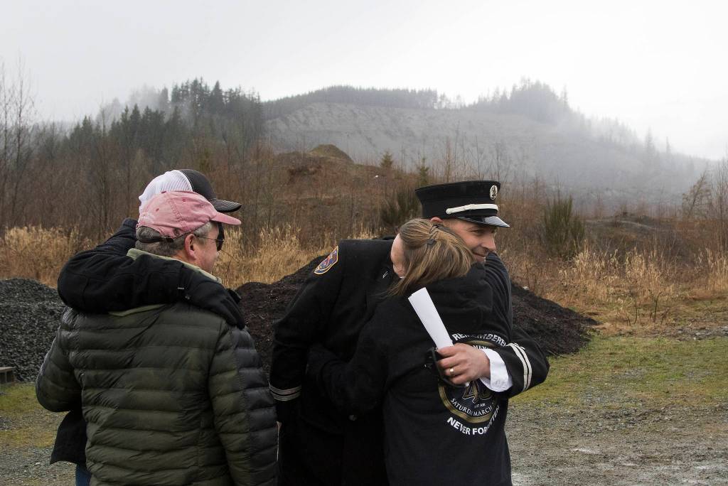 Oso Fire Department Capt. Tim Harper hugs Peggy Ray as family and friends gather on the seventh anniversary of the Oso landslide. (Andy Bronson / The Herald)