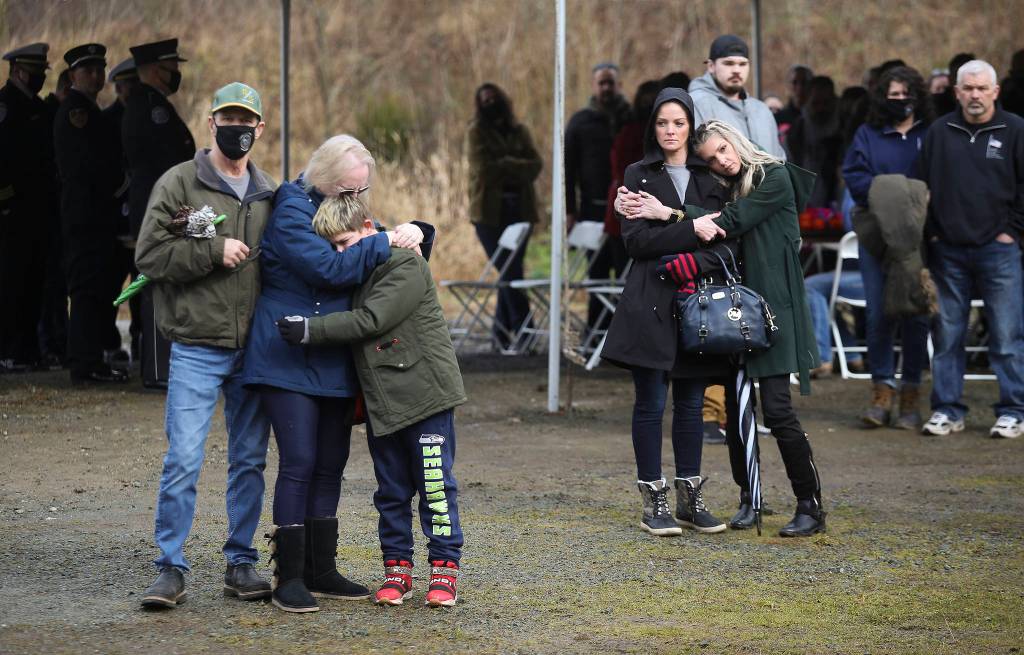 Family and friends of victims listen to a bagpiper play Amazing Grace at the end of a memorial ceremony marking the seventh anniversary of the Oso mudslide on Monday. (Andy Bronson / The Herald)