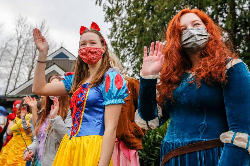 Michelle Fast (left) and Ellie Behn wave to incoming cars during a fundraiser at Lundeen Park in Lake Stevens on March 6. (Kevin Clark / The Herald)