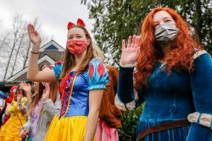 Michelle Fast, left, Ellie Behn wave to incoming cars Saturday morning at Lundeen Park in Lake Stevens on March 6, 2021. (Kevin Clark / The Herald)