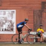 A portrait of the Nakashima family, who were sent to Japanese internment camps during World War II, fades in the sunlight as riders take a break at the Nakashima Barn at the north end of the Centennial Trail in Snohomish County on Sept. 2, 2019 in Arlington. (Andy Bronson / Herald file)