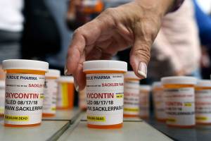 FILE - In this Aug. 17, 2018 file photo, family and friends who have lost loved ones to OxyContin and opioid overdoses leave pill bottles in protest outside the headquarters of Purdue Pharma, which is owned by the Sackler family, in Stamford, Conn. The company that has made billions selling the prescription painkiller OxyContin says it is considering bankruptcy as one of several possible legal options, in an email to The Associated Press. (AP Photo/Jessica Hill, File)
