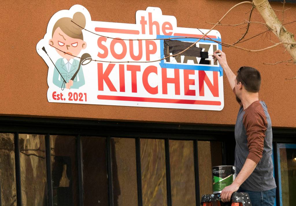 A man paints over the word Nazi at the Soup Nazi Kitchen on Hoyt Avenue on Wednesday in Everett. (Andy Bronson / The Herald)