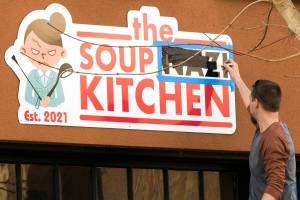 A man paints over the word "Nazi" at the Soup Nazi Kitchen on Hoyt Avenue on Wednesday, March 17, 2021 in Everett, Washington. Before even opening windows were smashed and graffiti was spray painted on a door of the restaurant run by Andrew Ho. (Andy Bronson / The Herald)