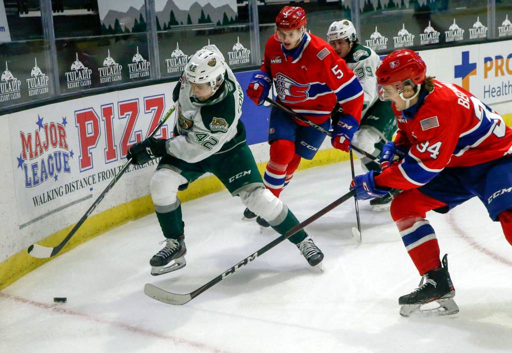 Silvertips Cole Fonstad races for a rebound with Chiefs Jordan Chudley and Chiefs Adam Beckman giving chase Saturday night at Angel of the Winds Arena in Everett on March 20, 2021. (Kevin Clark / The Herald)