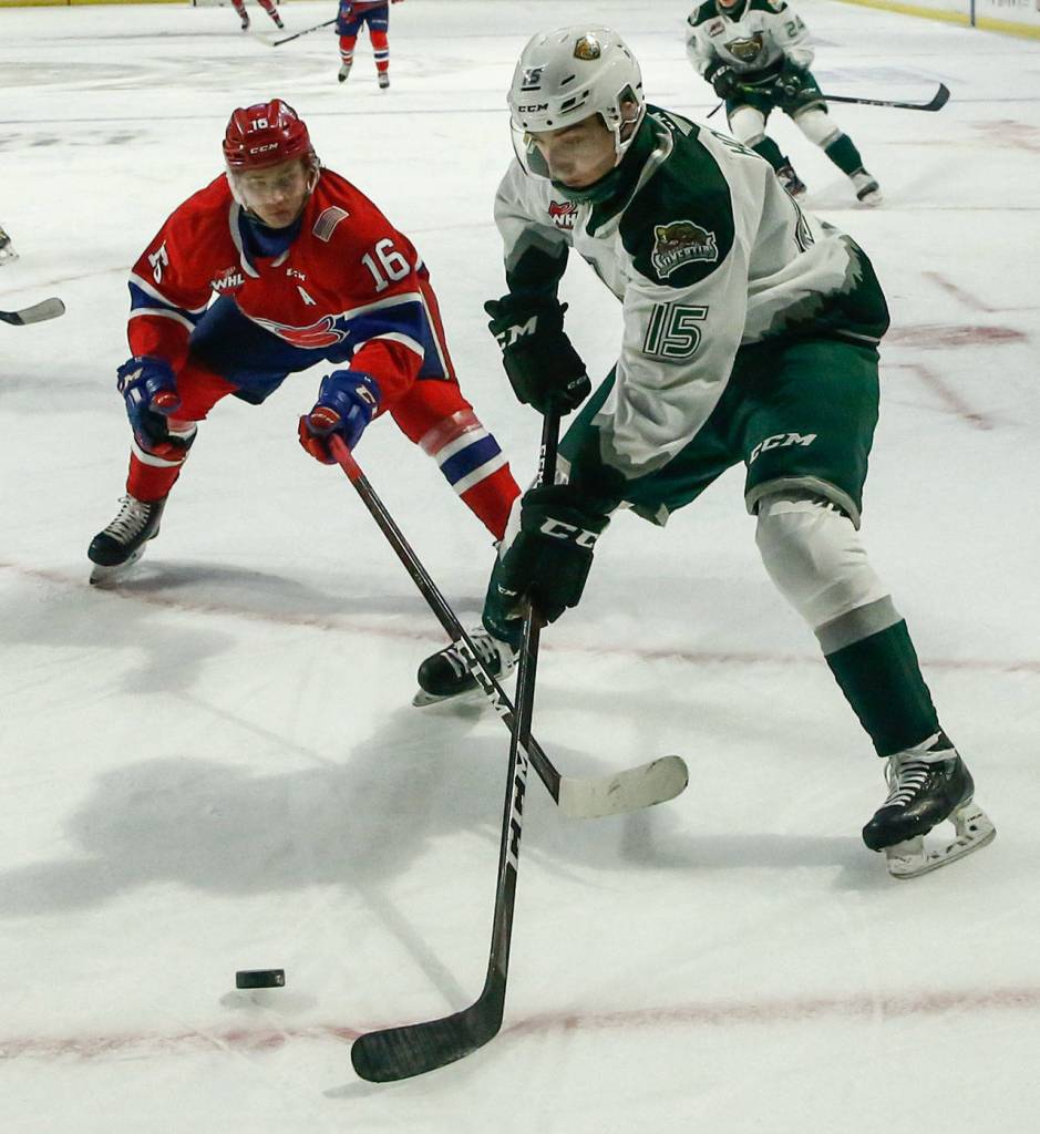 Silvertips Ryan Hofer controls the puck with Chiefs Cordel Larson trailing Saturday night at Angel of the Winds Arena in Everett on March 20, 2021. (Kevin Clark / The Herald)