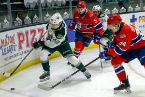 Silvertips' Cole Fonstad races for a rebound with Chiefs' Jordan Chudley and Chiefs' Adam Beckman giving chase Saturday night at Angel of the Winds Arena in Everett on March 20, 2021. (Kevin Clark / The Herald)