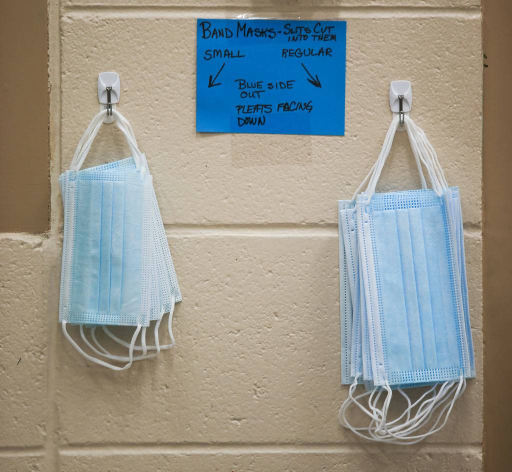 Masks hang on a wall at Haller Middle School during band practice Thursday in Arlington. (Andy Bronson / The Herald)