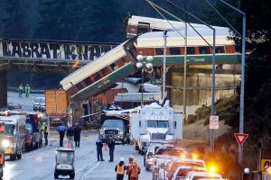 Lights illuminate cars from an Amtrak train that derailed above Interstate 5, Monday, Dec. 18, 2017, in DuPont, Wash. The Amtrak train making the first-ever run along a faster new route hurtled off the overpass Monday near Tacoma and spilled some of its cars onto the highway below, killing several people, authorities said. (AP Photo/Elaine Thompson)