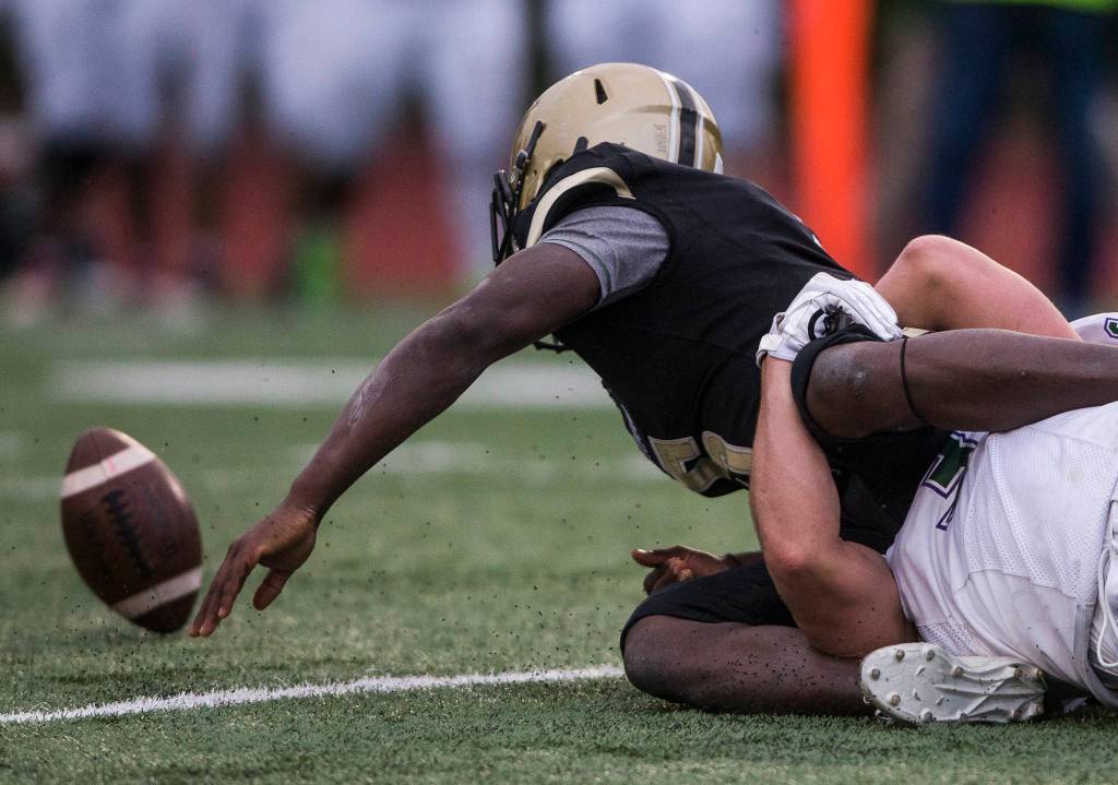 Lynnwoods Noel Gougouehi reaches out after the football after fumbling when being tackled by Edmonds-Woodways Ryan Fahey during the game on Friday, March 26, 2021 in Edmonds, Wa. (Olivia Vanni / The Herald)