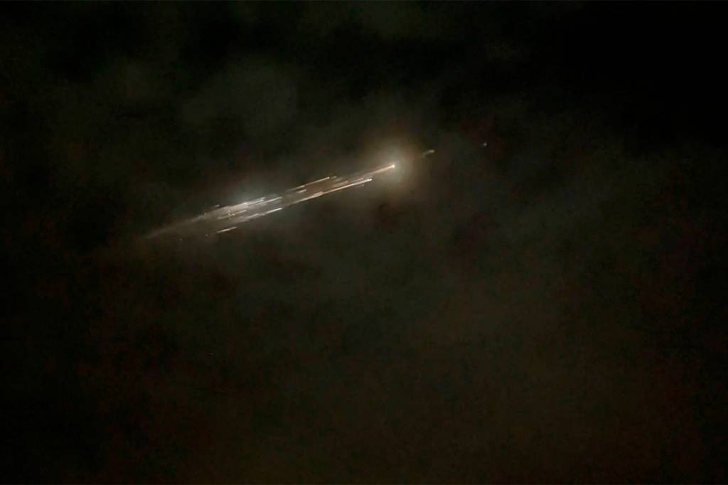 In this image taken from video, debris from a SpaceX rocket lights up the sky behind clouds over Vancouver, Washington, on Thursday evening. (Roman Puzhlyakov via AP)