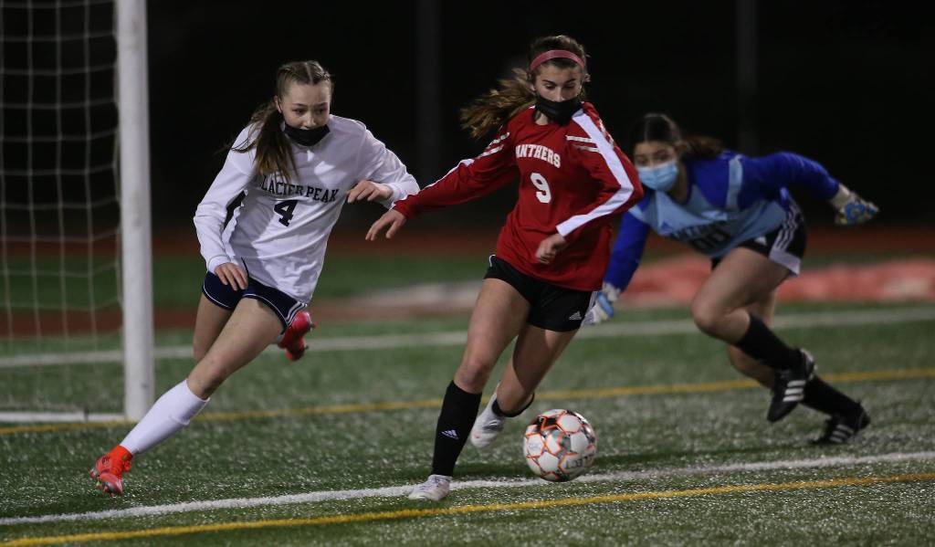 With goalie Kali Cole (rear) scrambling back to her post, Glacier Peaks Ella Seelhoff tries to beat Snohomishs Jenna Edelbrock to the ball during a girls soccer match at Veterans Memorial Stadium on Monday in Snohomish. (Andy Bronson / The Herald)